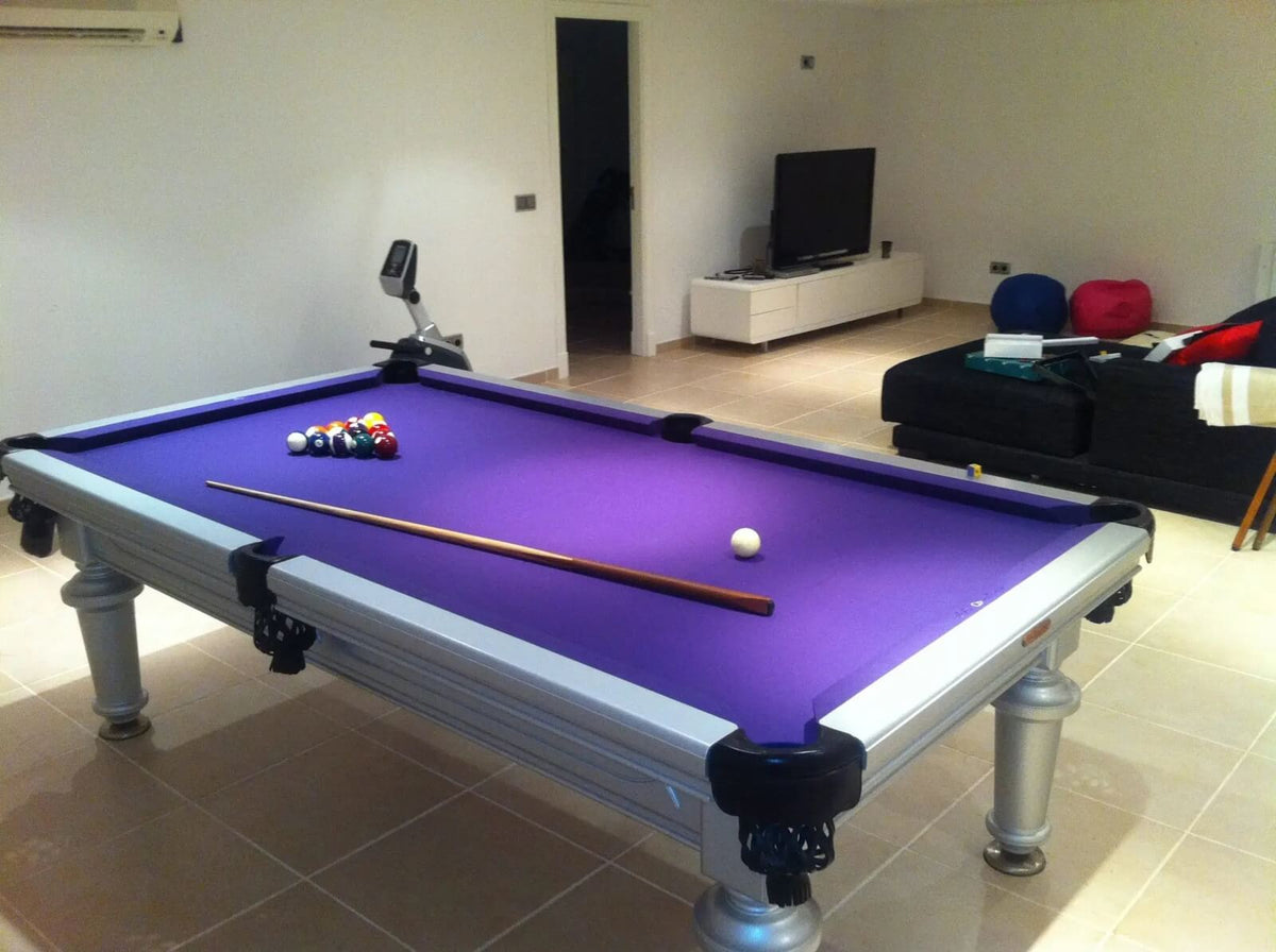 American pool table with purple cloth and a silver cabinet in a living room