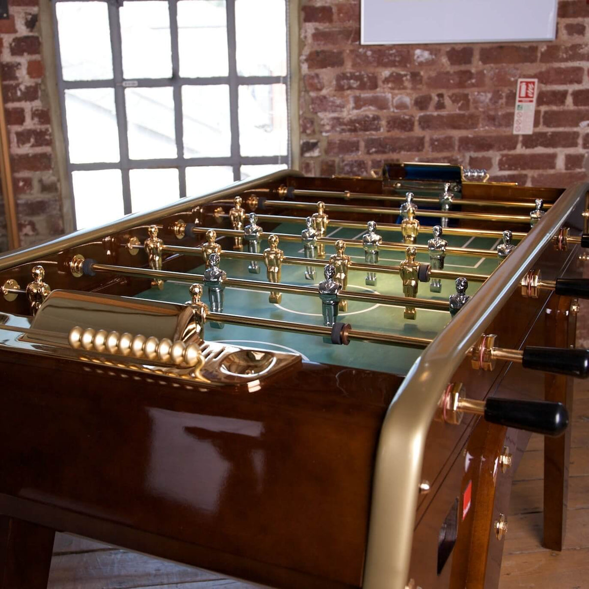 B50 special edition football table in a brick-walled room beside a tall window