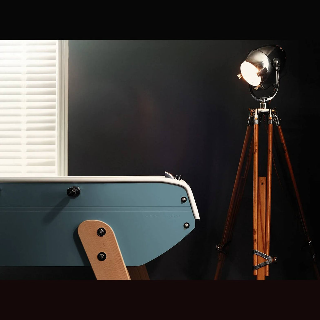 Light blue Eames inspired B90 football table end with beech leg beside a tripod floor lamp