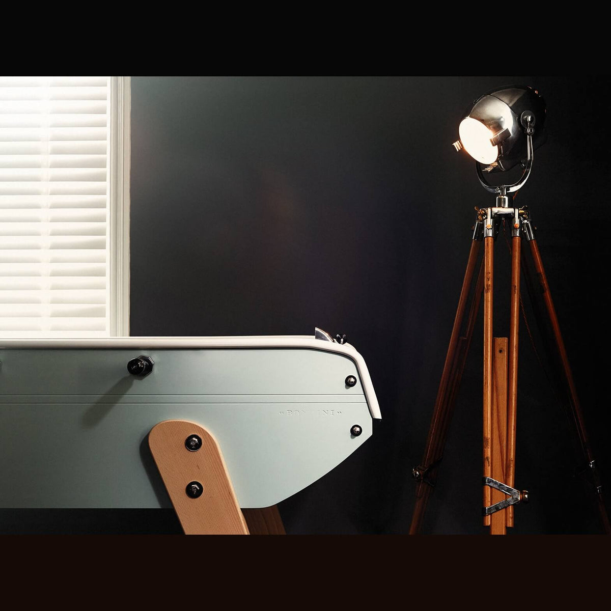 Pale Eames inspired B90 football table end lit by a tripod floor lamp