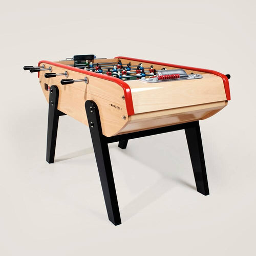Bonzini B90 football table in natural beech with red rails and black legs, three-quarter view