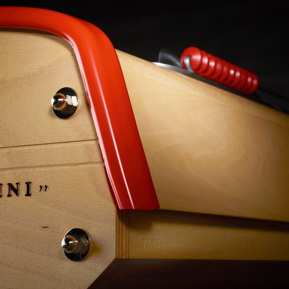 Corner of the B90 football table's beech cabinet with red rail and chrome rod bearings