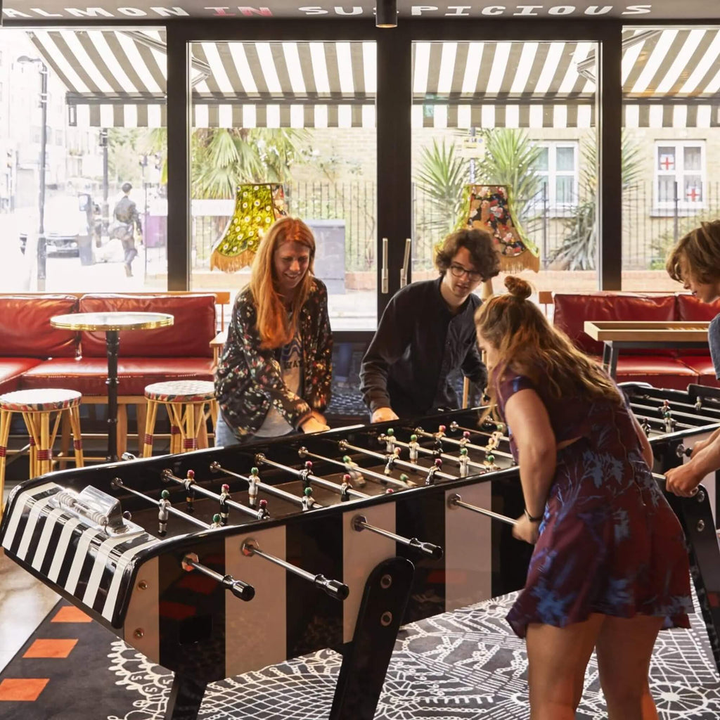 Group of friends playing on a Bonzini giant football table in a bright venue