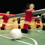 Red Bonzini players in motion striking a white ball on the green pitch
