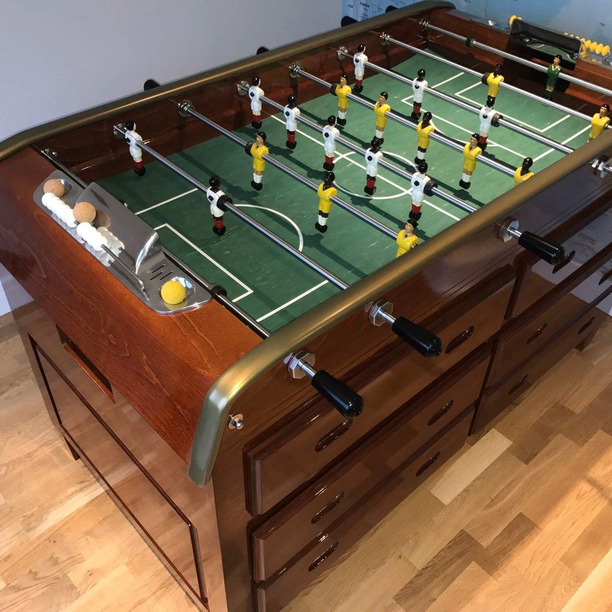 Green pitch and players on the cherry wood Grand Tiroirs football table