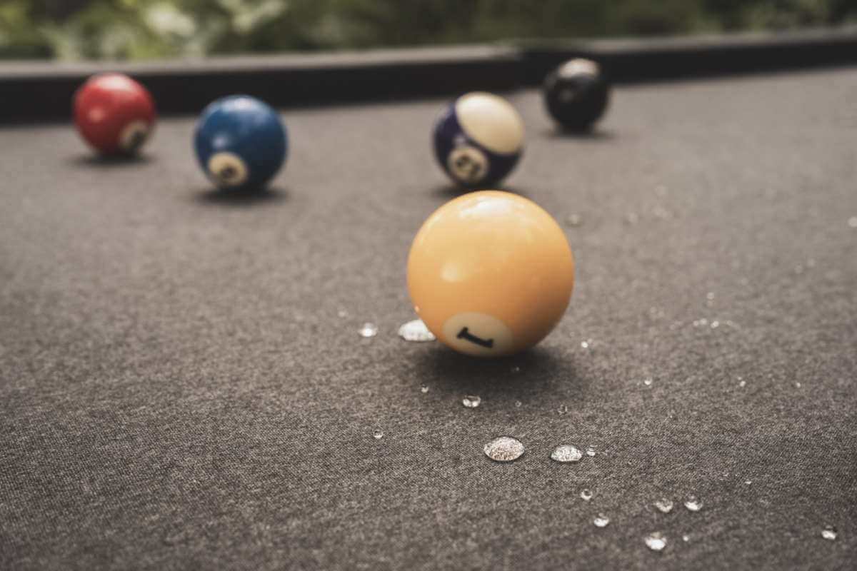 Black Cornilleau Origin outdoor pool table outside in a garden setting, alternate angle