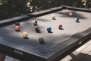 Black Cornilleau Origin outdoor pool table outside in a garden setting