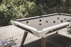 White Cornilleau Origin outdoor pool table set up on a patio, angled view