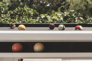 White Cornilleau Origin outdoor pool table outside in a garden setting