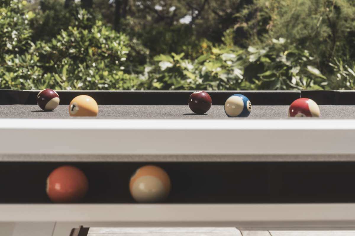 White Cornilleau Origin outdoor pool table outside in a garden setting
