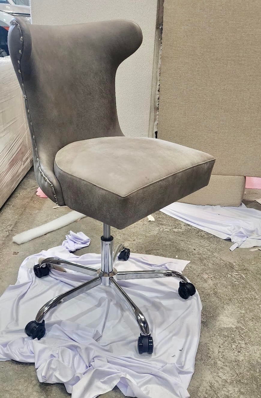 Grey leather poker chair with stud trim on a chrome swivel base with castors