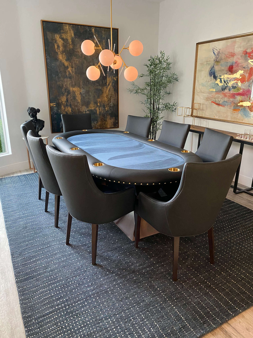 Grey leather poker chairs around an oval poker table in a dining room