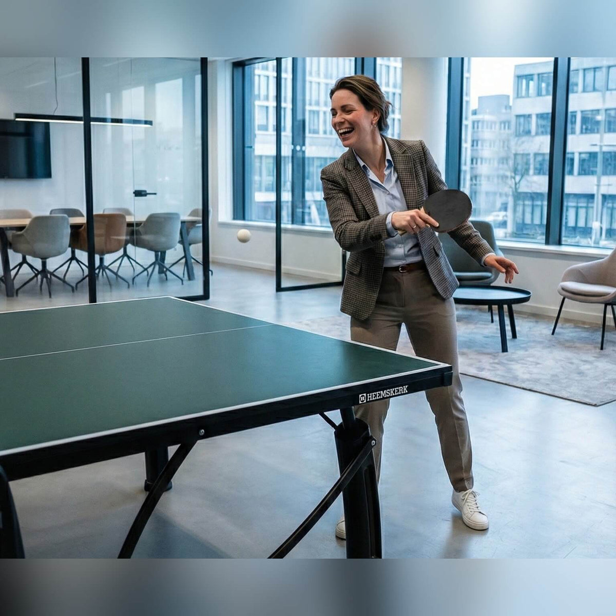 Woman playing on a green Heemskerk 2250 indoor table tennis table in an office