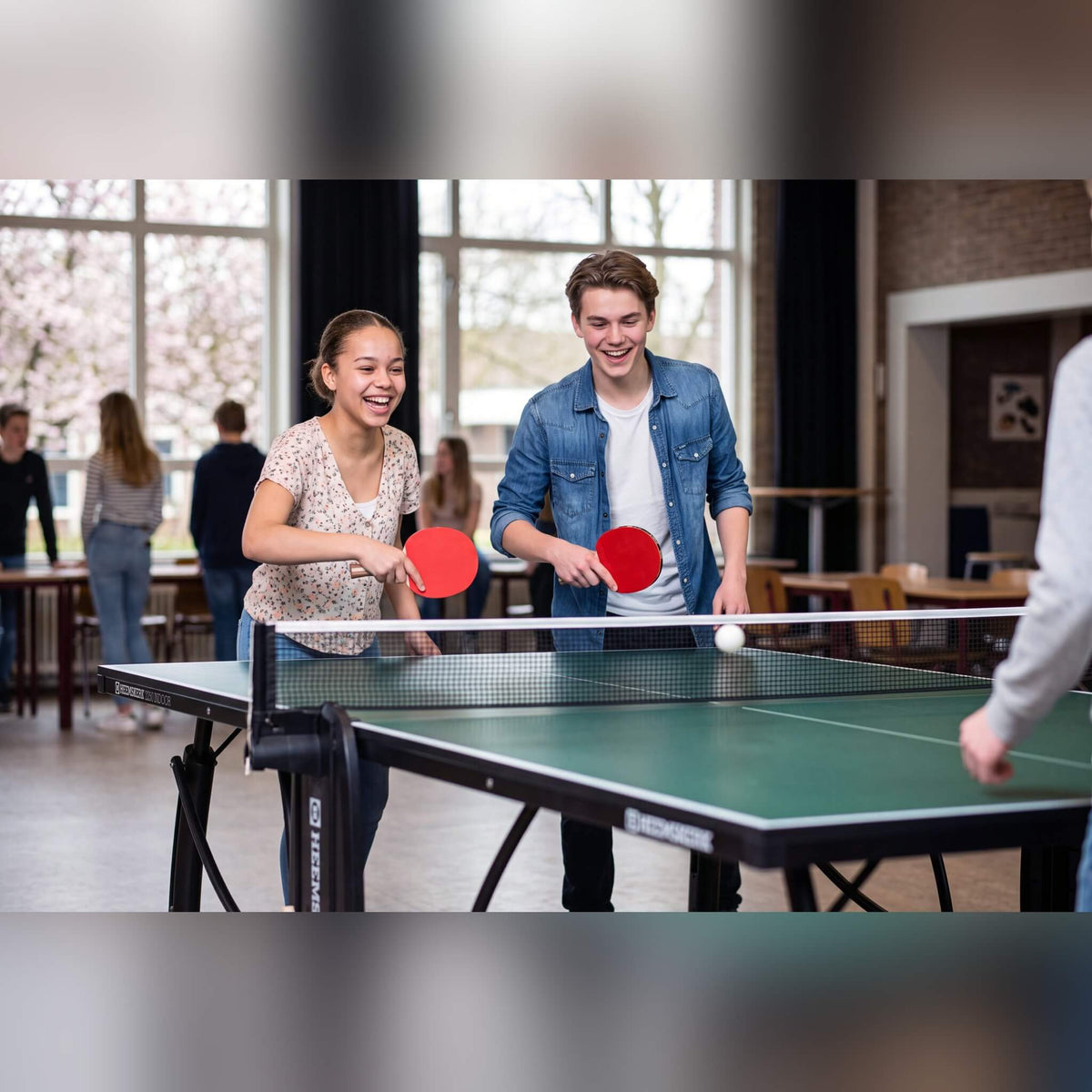 Two students playing on a green Heemskerk 2250 indoor table tennis table at school