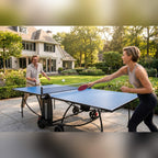 Couple playing on a blue Heemskerk 1900 outdoor table tennis table on a garden patio