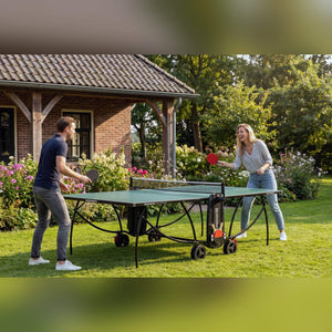 Couple playing on a green Heemskerk 1900 outdoor table tennis table in a garden