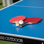 Bats and ball on the blue top of a Heemskerk 2300 outdoor table tennis table