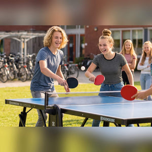 Students playing on a blue Heemskerk 2300 outdoor table tennis table outside a school