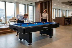 Two people playing pool on a Heemskerk Baltimore with blue cloth in an office