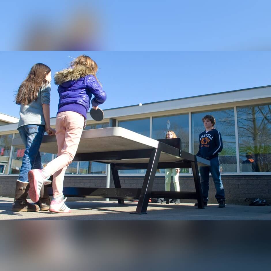 Children playing on a Heemskerk Beta concrete outdoor table tennis table outside a school