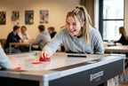 Smiling woman playing on the Heemskerk Coliseum air hockey table in a canteen