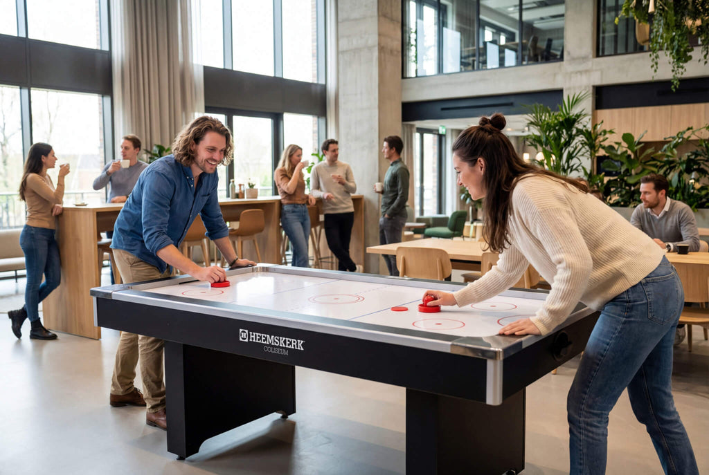Two people playing on the Heemskerk Coliseum air hockey table in a busy canteen