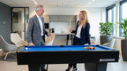 Two colleagues talking next to a Heemskerk Dallas pool table with blue cloth in a modern office