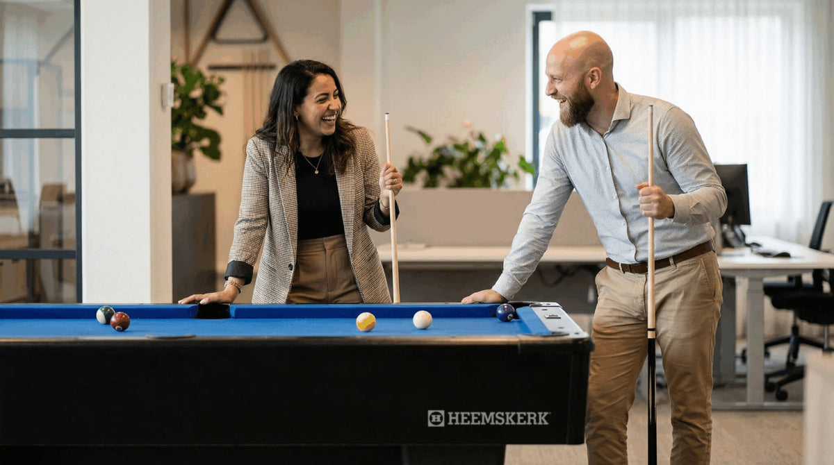 Colleagues chatting beside a Heemskerk Dallas pool table with blue cloth in an office