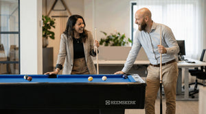 Colleagues chatting beside a Heemskerk Dallas pool table with blue cloth in an office
