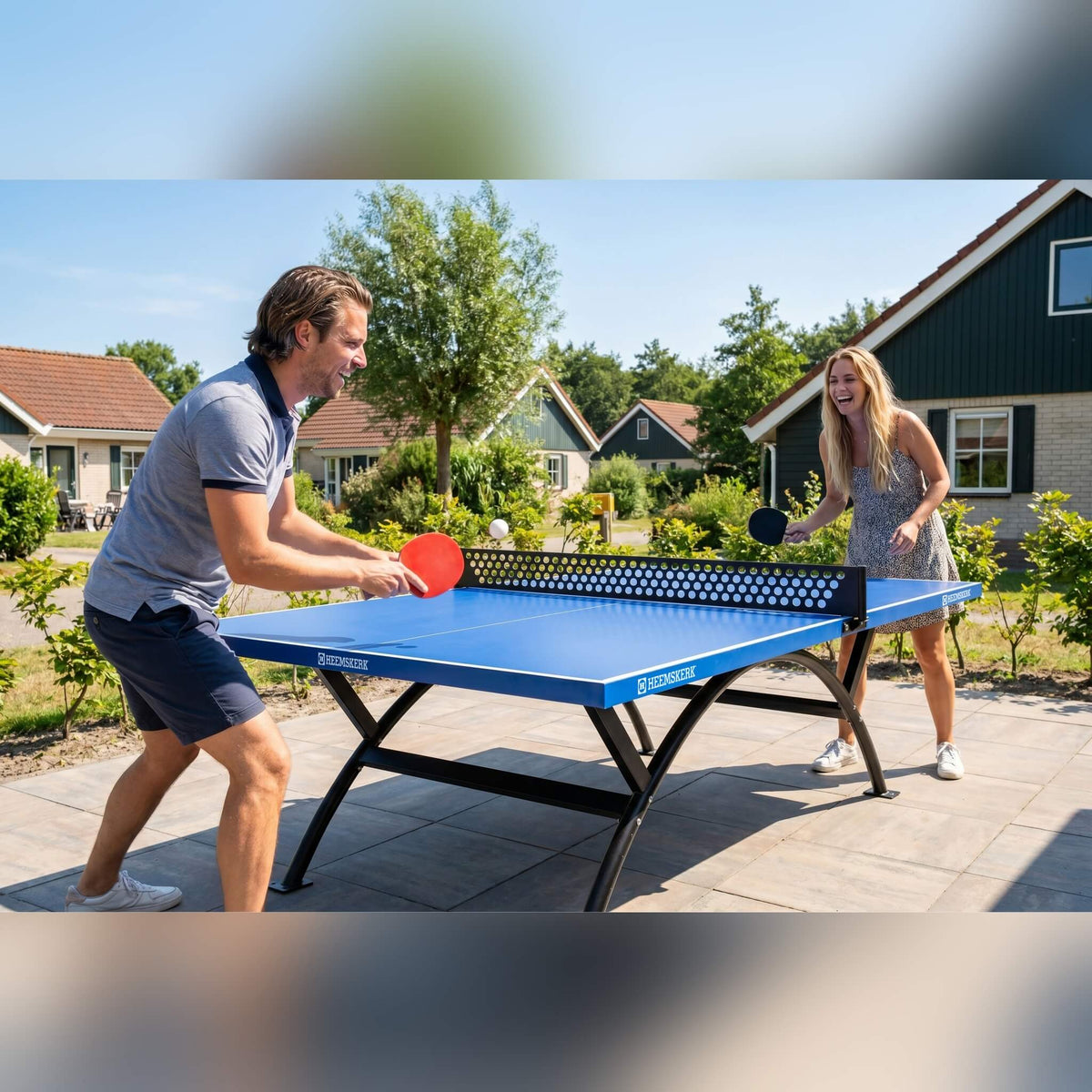 Two people playing on a Heemskerk Lima outdoor table tennis table at a holiday park