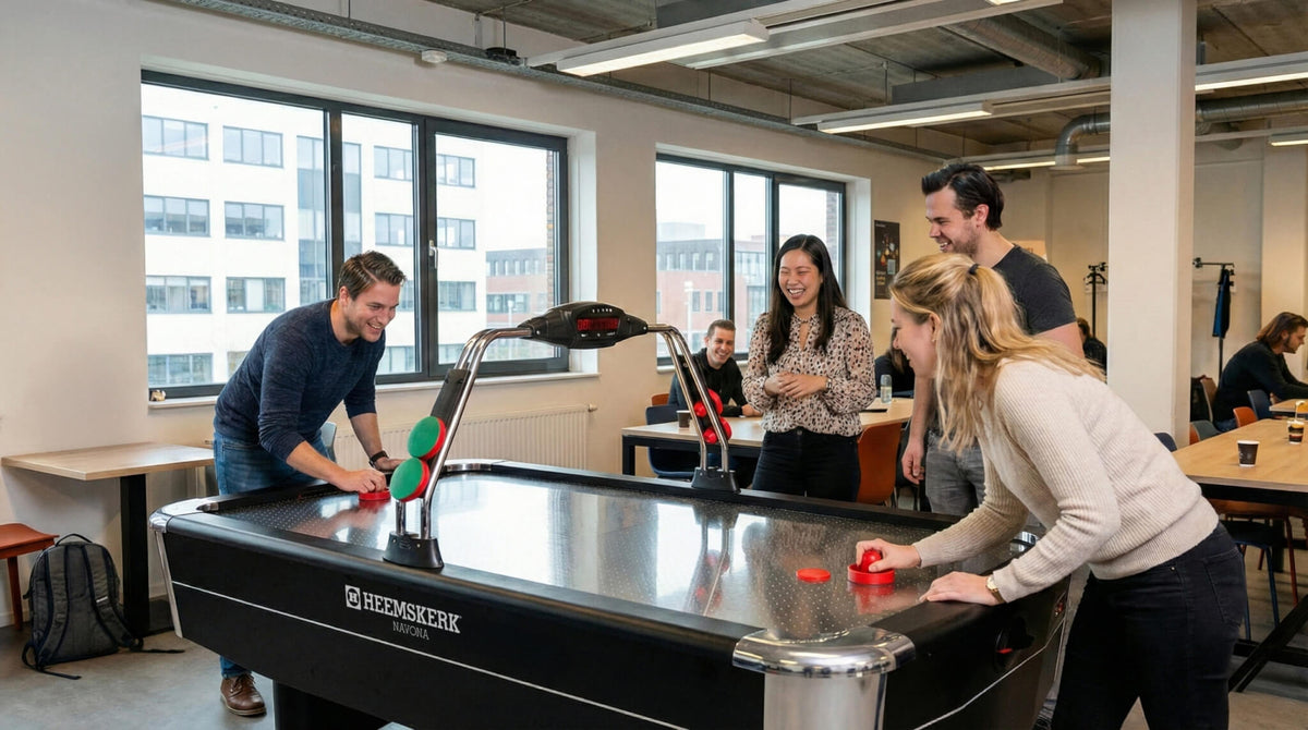 Colleagues playing a game on the Heemskerk Navona air hockey table in an open-plan office