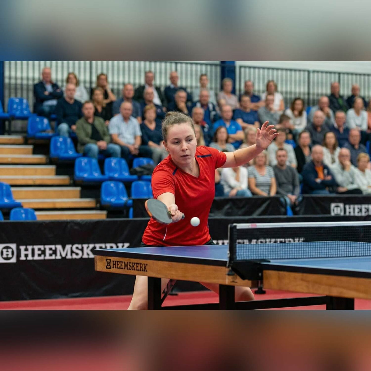Player returning a shot on a blue Heemskerk Novi 2400 table tennis table at a match