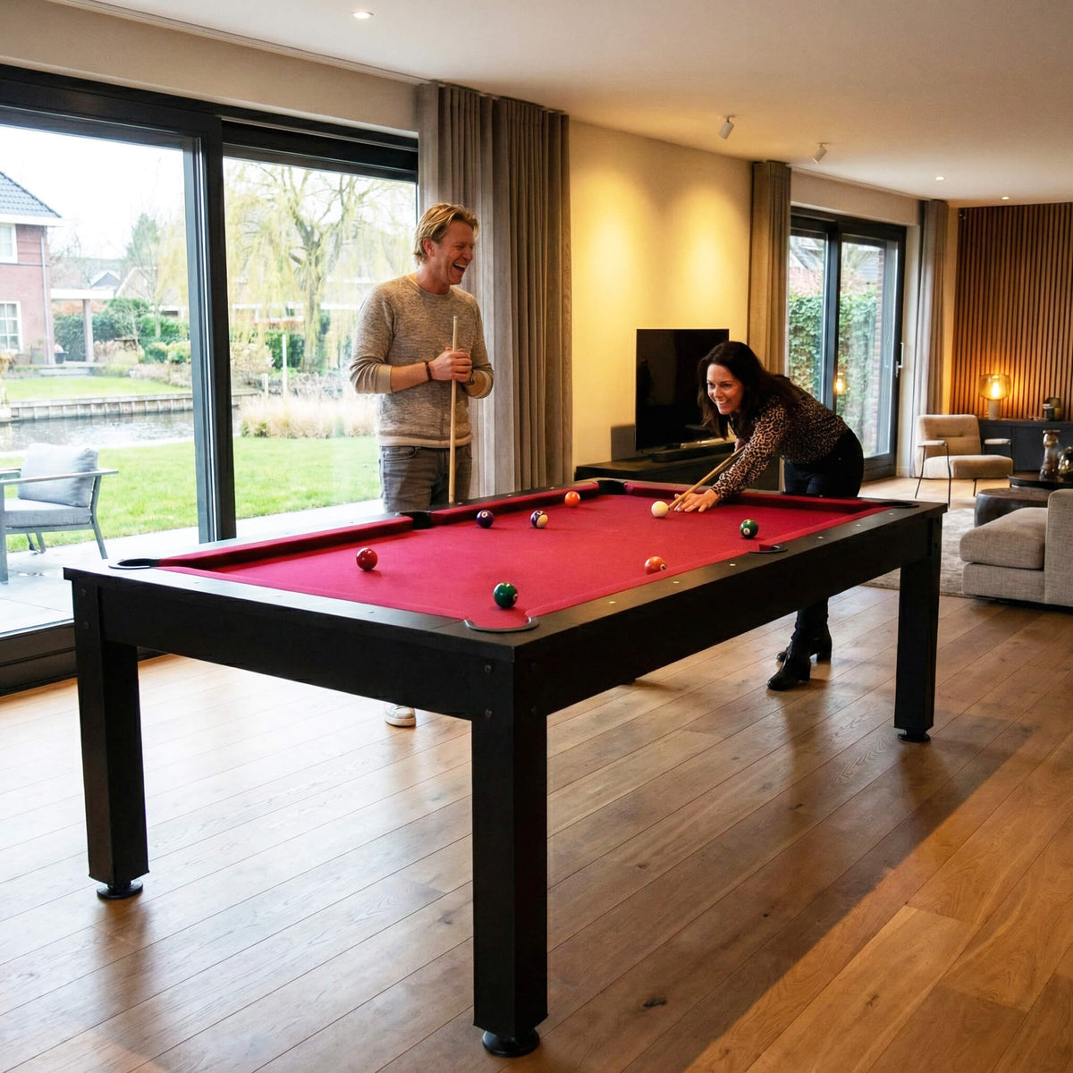 Two people playing pool on the black Heemskerk Richmond in a bright living room