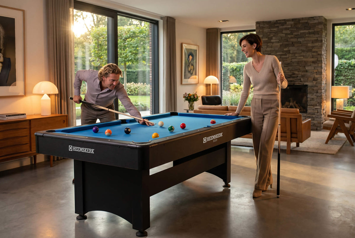 Two people playing pool on the black Heemskerk Solid Feet table in a bright living room