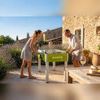 Couple playing on a Heemskerk Sunshine outdoor football table on a sunny terrace