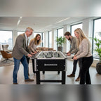 Four colleagues playing on a Heemskerk TacTic football table in an office