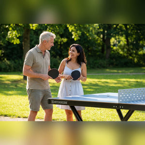 Couple holding bats beside a Heemskerk Tango outdoor table tennis table in a park