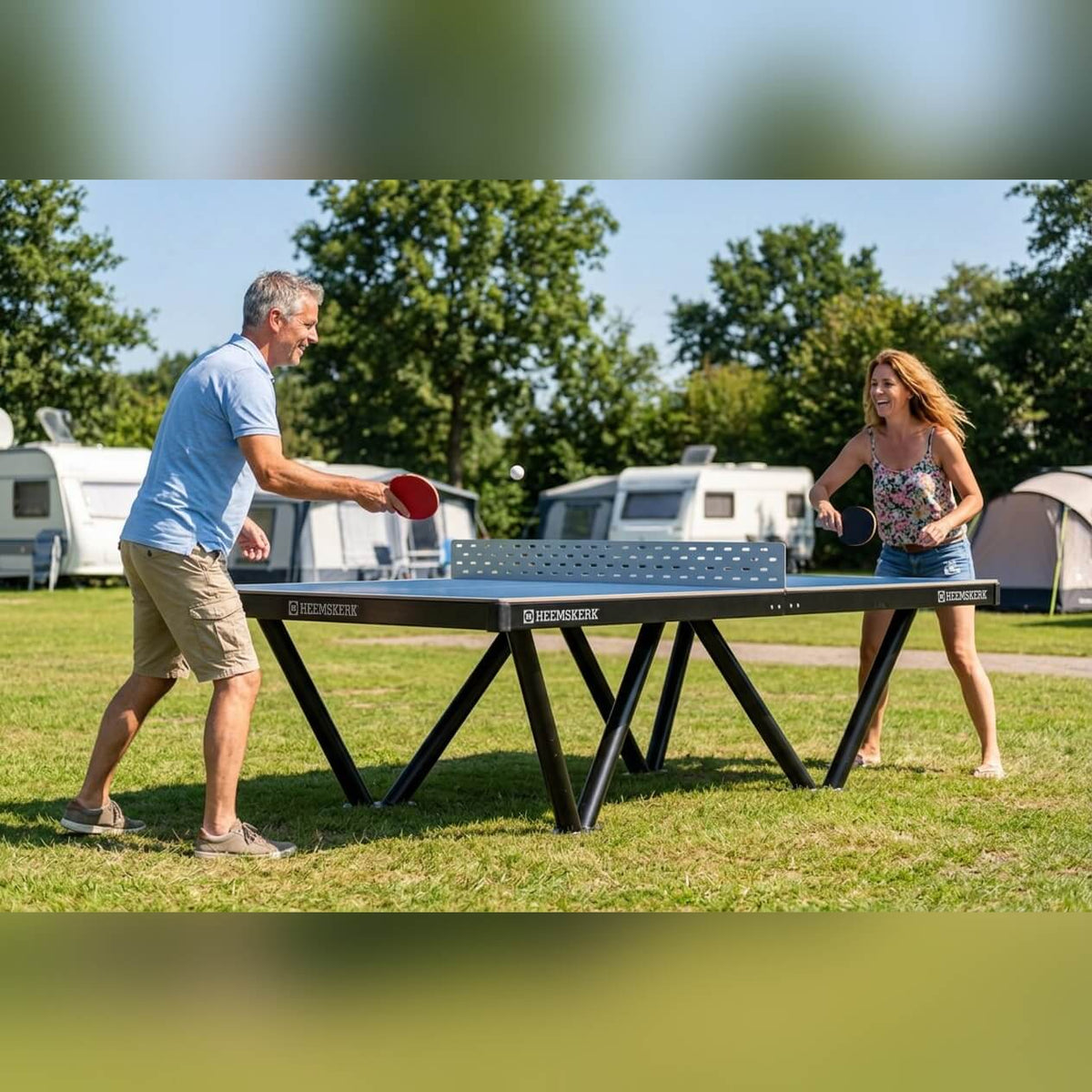 Two people playing on a Heemskerk Tango outdoor table tennis table at a campsite