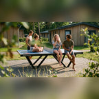 Teenagers sitting on a Heemskerk Tango outdoor table tennis table at a holiday park
