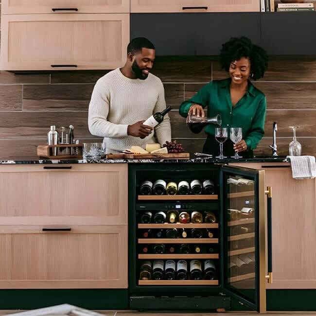 Couple pouring wine in a kitchen beside a Kaiser Art Deco wine fridge with the door open