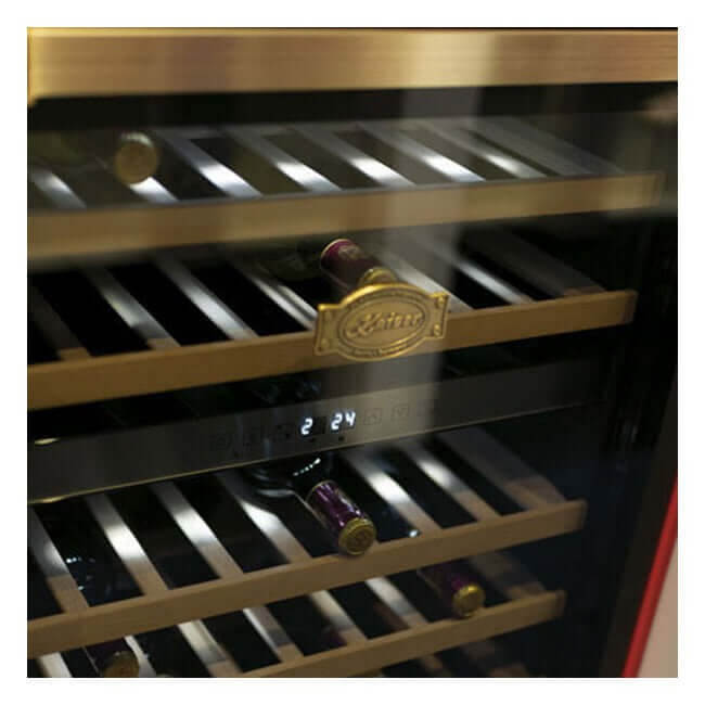 Wine bottles on wooden shelves behind the glass door of a Kaiser Art Deco wine fridge