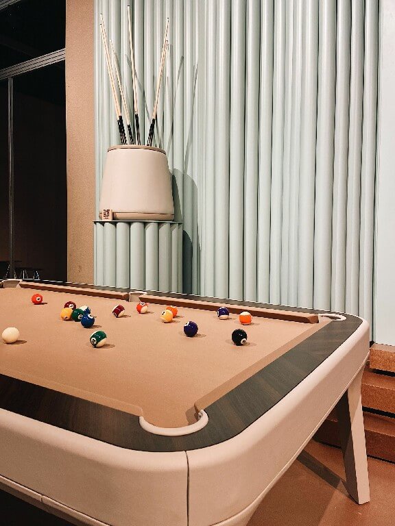 Corner of a Luxury Dandy pool table with coral cloth and ebony makassar rail