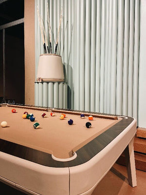 Corner of a Luxury Dandy pool table with coral cloth and ebony makassar rail