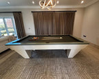 Luxury Newde pool table with ivory ribbed legs and a sage grey lacquered top rail in a modern living room