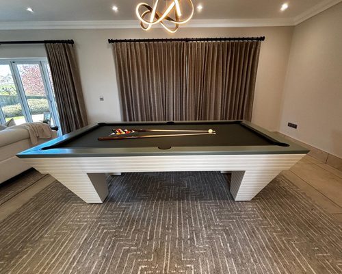 Luxury Newde pool table with ivory ribbed legs and a sage grey lacquered top rail in a modern living room