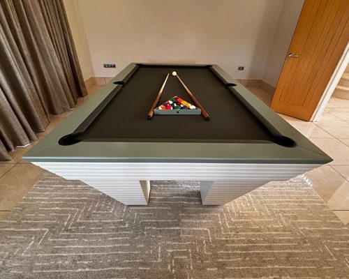 Luxury Newde pool table with racked balls and cues on dark grey cloth