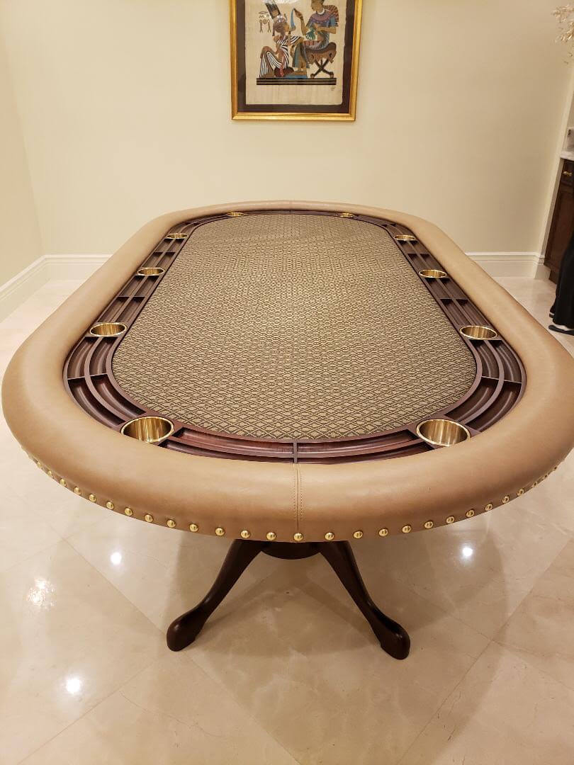 Luxury oval poker table with tan leather rail, brass studs, mahogany racetrack and brass cupholders on a pedestal base