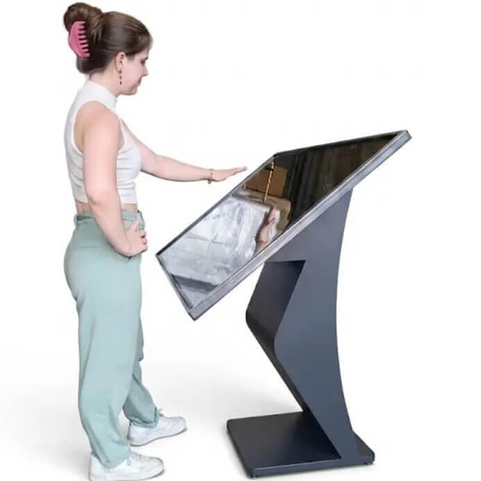 A woman using an angled touchscreen kiosk