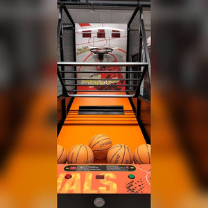 Basketball arcade machine lit up in a dark room