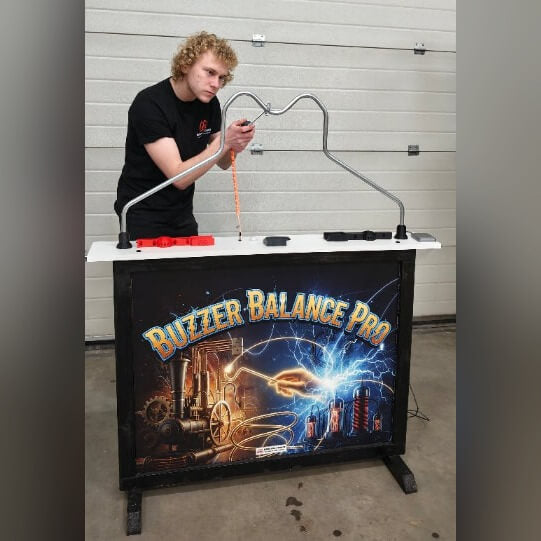 A man playing the MadeForArcade Buzzer Balance Pro buzz wire game at an exhibition stand